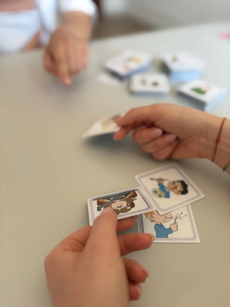 Due mani che giocano con carte illustrate durante un’attività in studio